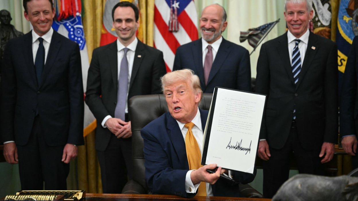 US President Donald Trump holds a singed executive order about quantum computing in the Oval Office of the White House